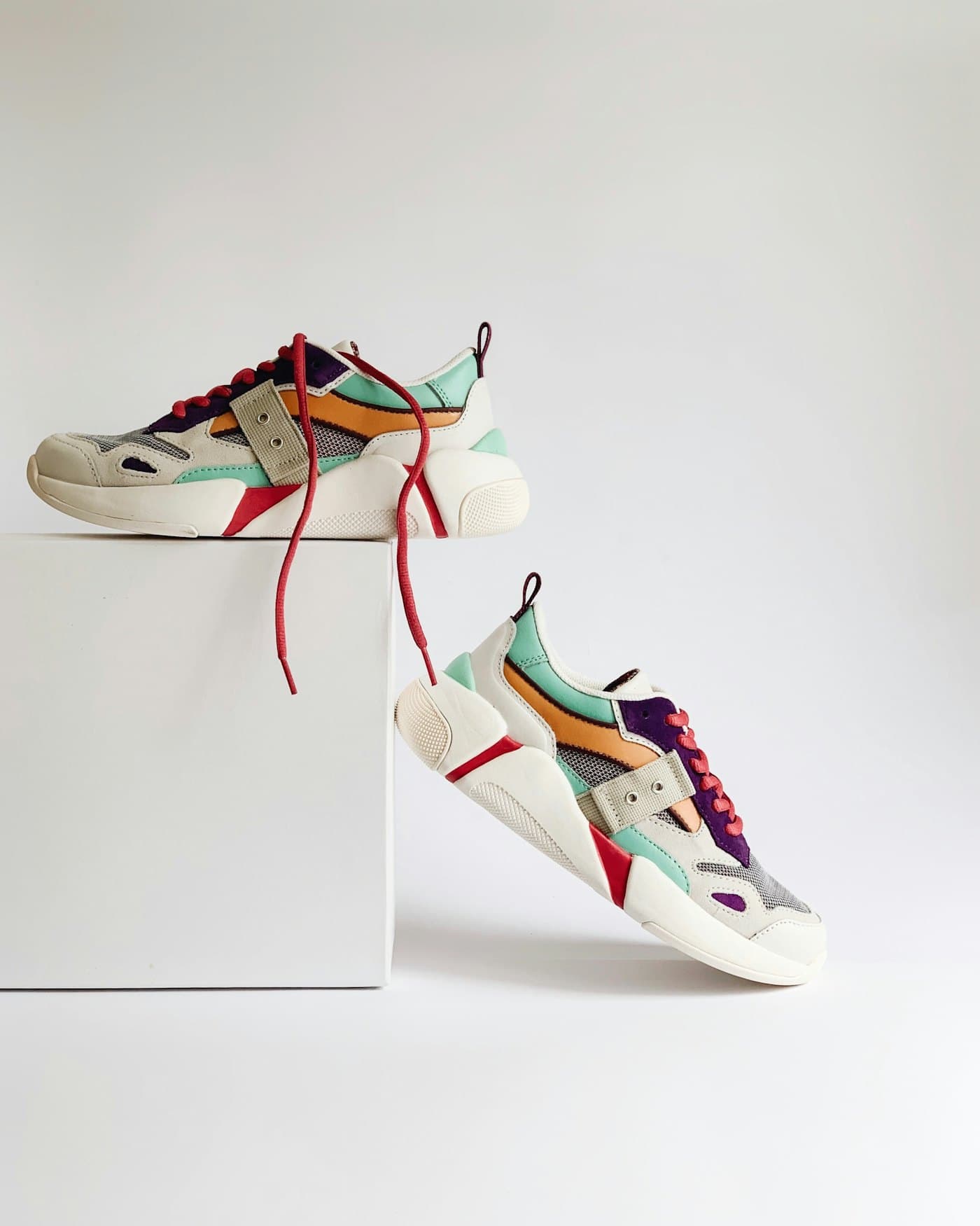 Pair of colour-blocked sneakers styled on a white plinth
