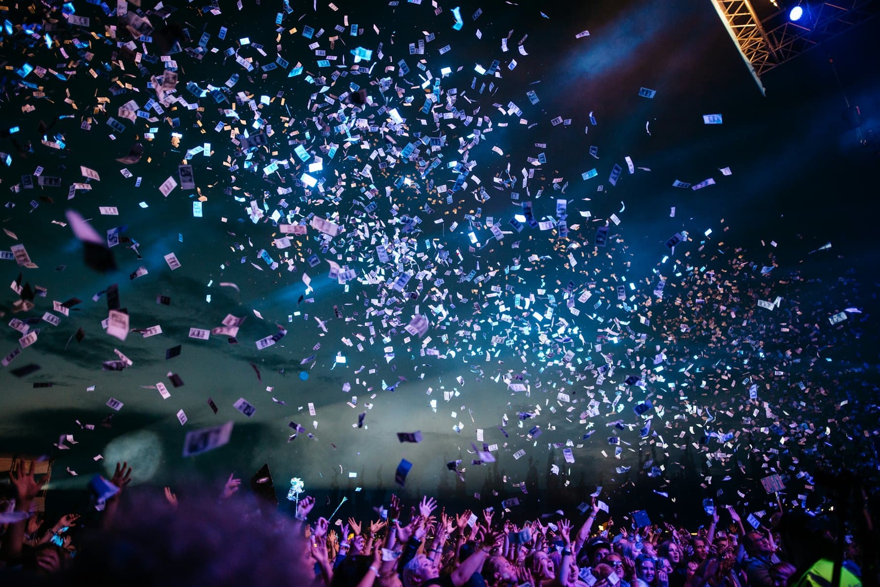 Concert crowd under a blizzard of confetti and stage lights