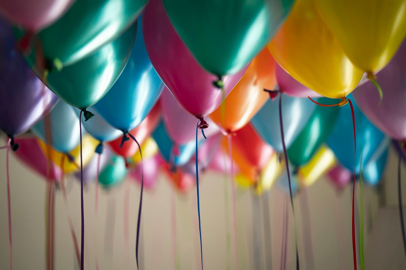Ceiling of bright metallic party balloons with trailing ribbons