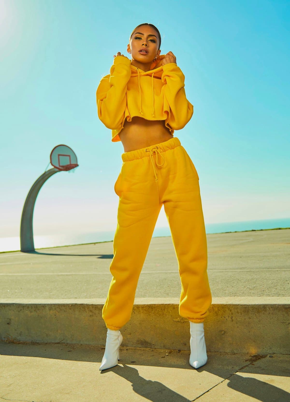 Model in a bright yellow tracksuit posing on an outdoor basketball court